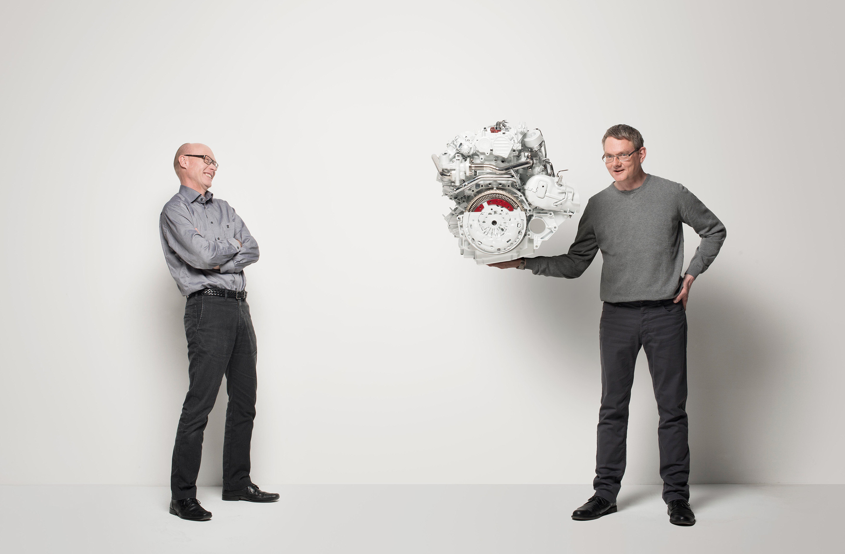 Two men beside an engine in a playful studio portrait for Volvo Cars